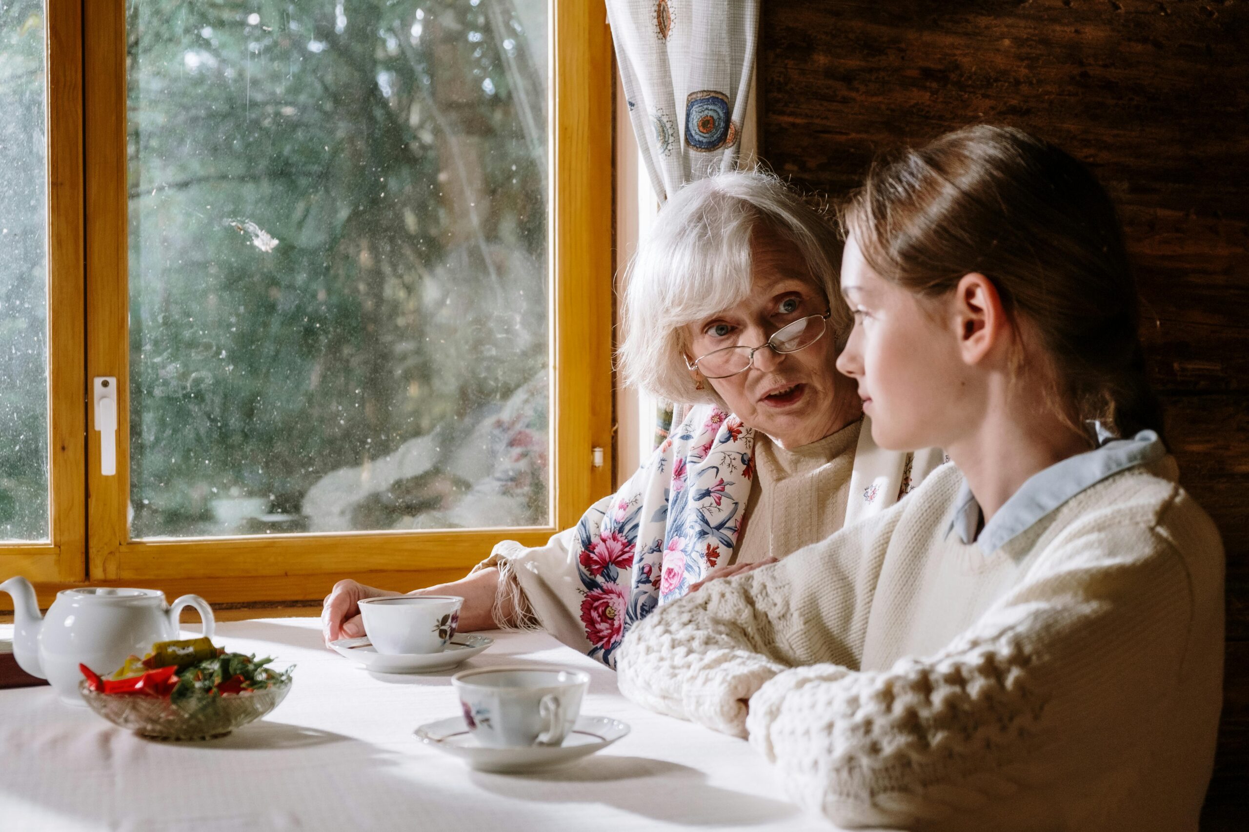 Older woman discussing documents with a younger woman at a table, representing financial guidance across life stages