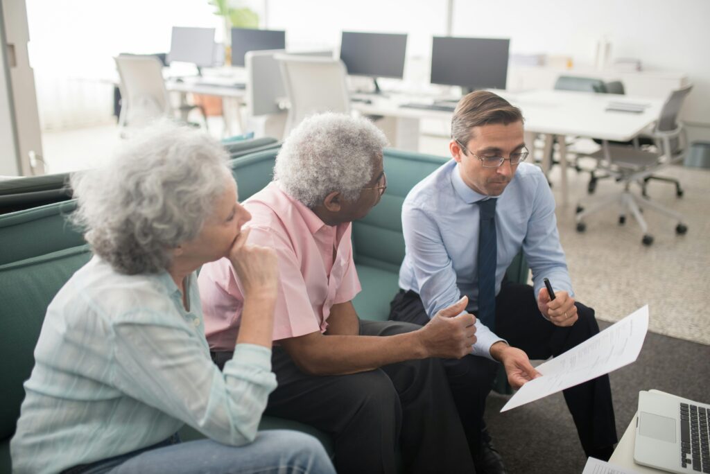 Elderly couple discussing pensions with a financial adviser in an office
