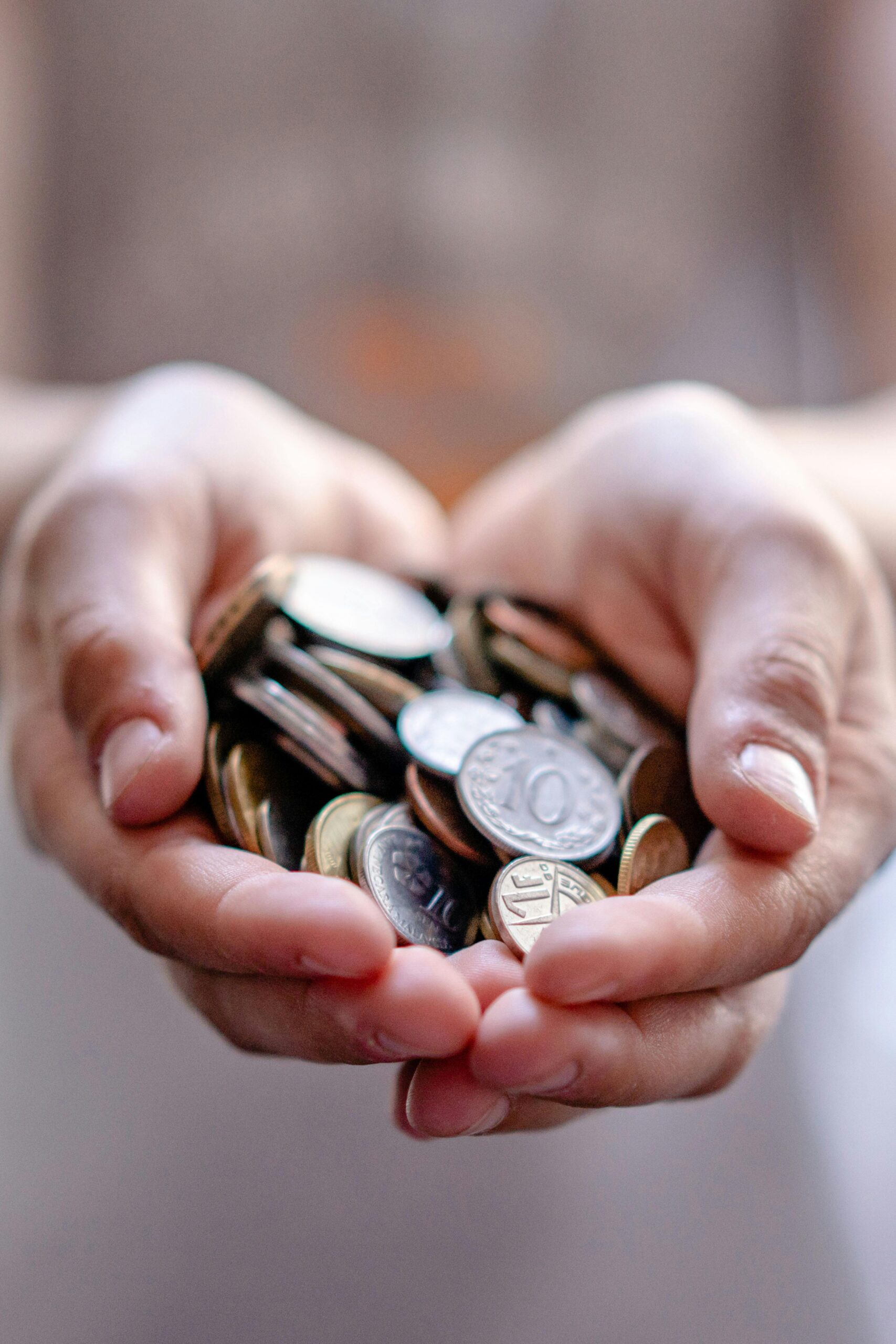 Hand holding a collection of saved coins, representing investing, savings and long-term financial planning.
