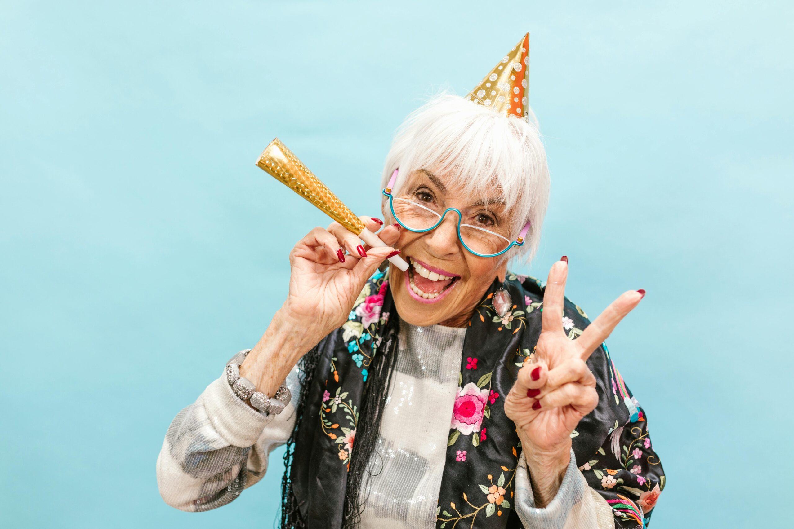 Smiling older woman celebrating her birthday with a balloon and party hat